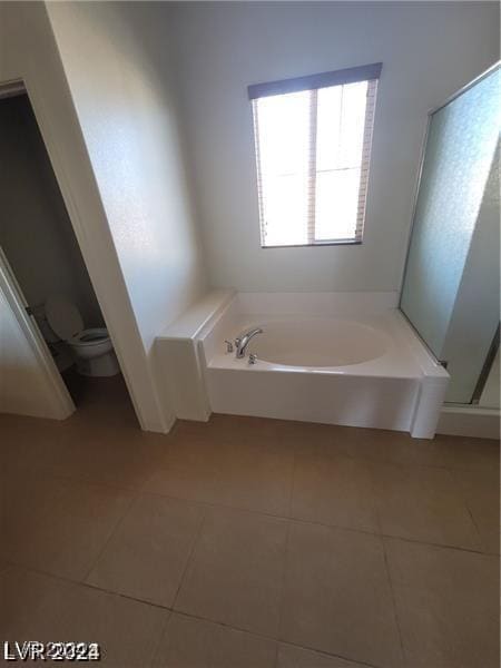 bathroom featuring tile patterned flooring, toilet, a bath, and walk in shower