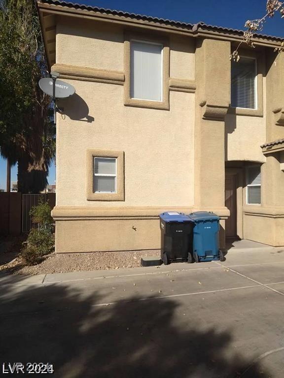 view of side of home with stucco siding and fence