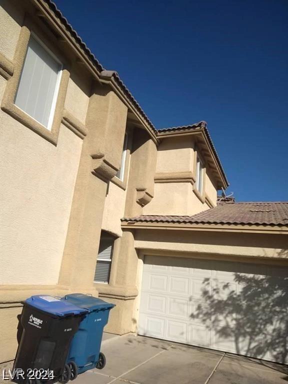 view of home's exterior with concrete driveway, a tiled roof, and stucco siding