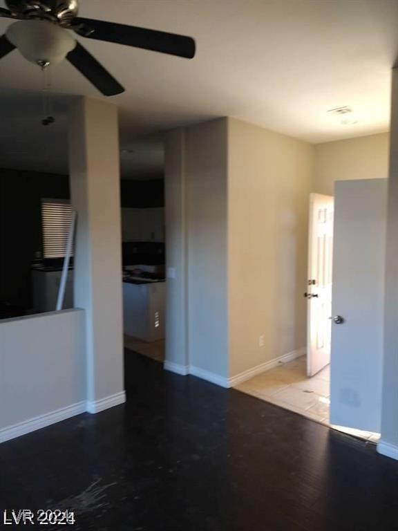 unfurnished living room featuring a ceiling fan and baseboards