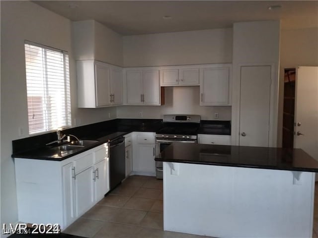 kitchen featuring stainless steel range oven, white cabinets, a breakfast bar, sink, and light tile patterned floors