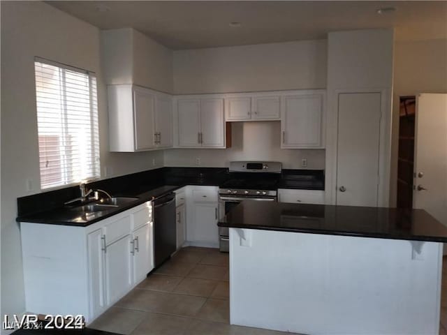 kitchen featuring dark countertops, dishwasher, stainless steel electric range oven, white cabinetry, and a sink