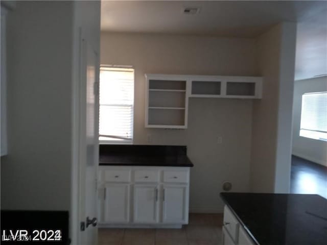 kitchen with light tile patterned floors, white cabinets, and plenty of natural light