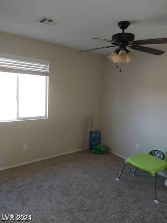 carpeted empty room featuring visible vents and ceiling fan