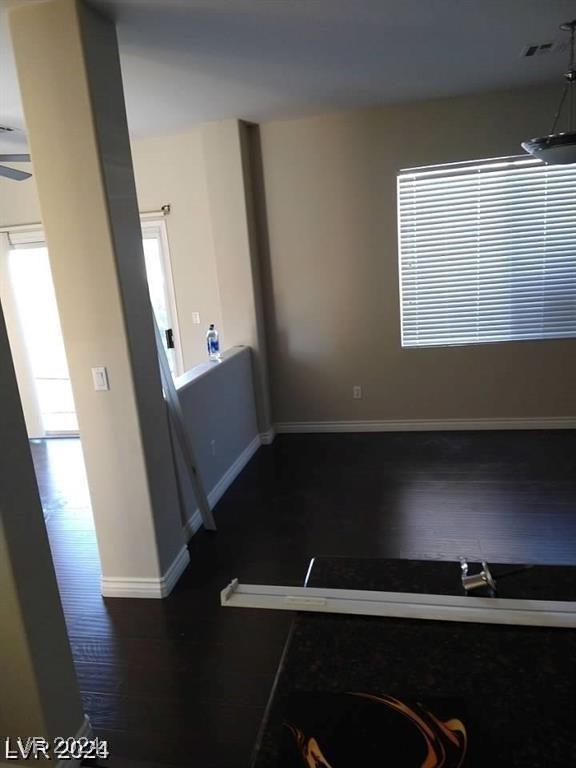 empty room featuring visible vents, wood finished floors, and baseboards