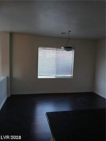 unfurnished dining area featuring dark wood-style floors and baseboards