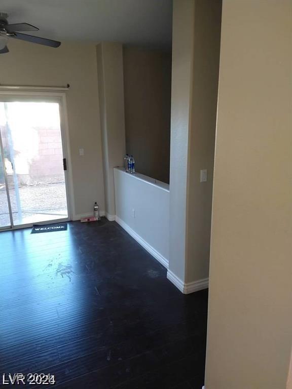 empty room with dark wood-style floors, baseboards, and ceiling fan