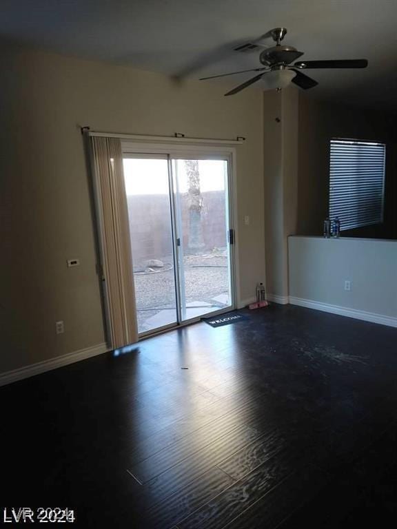 spare room with a ceiling fan, dark wood-style floors, and baseboards