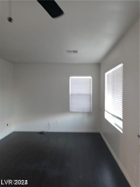 empty room featuring visible vents, baseboards, and wood finished floors