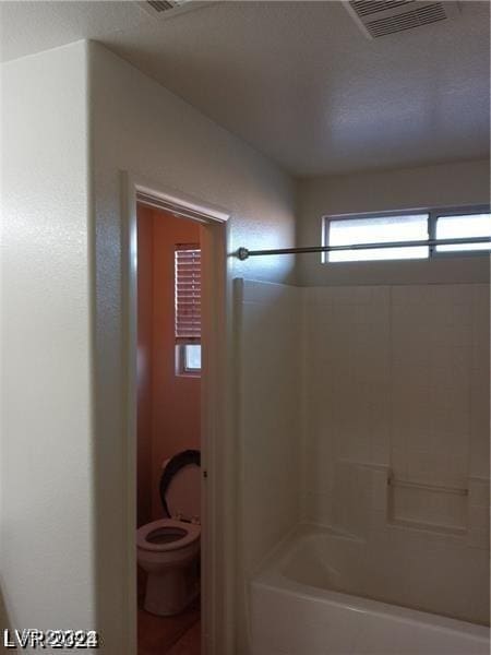 bathroom with shower / tub combination, toilet, and visible vents