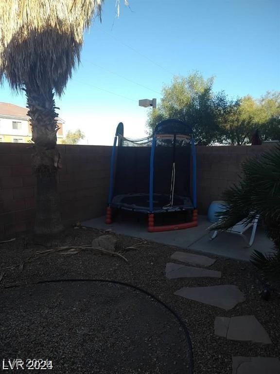 view of yard featuring a trampoline and a fenced backyard