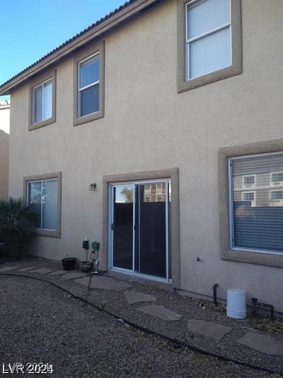 rear view of house featuring stucco siding