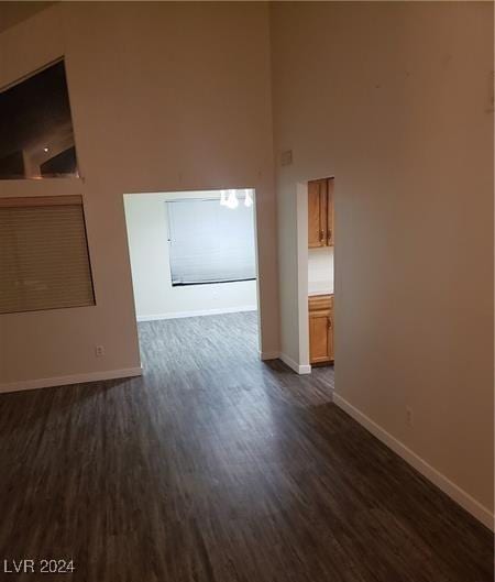 unfurnished room featuring a towering ceiling and dark wood-type flooring