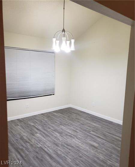 empty room featuring a chandelier, hardwood / wood-style flooring, and vaulted ceiling