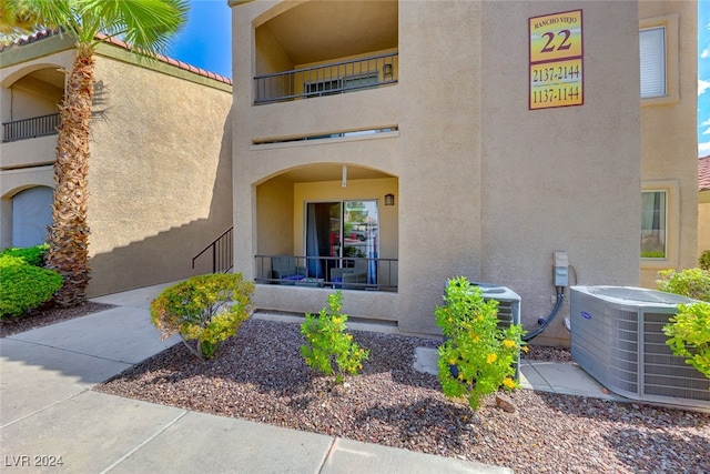 view of exterior entry featuring a balcony and central air condition unit