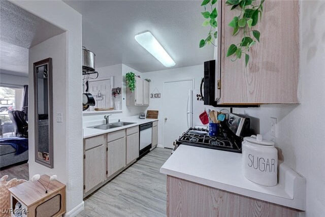 kitchen with sink, white dishwasher, a textured ceiling, and range with gas cooktop