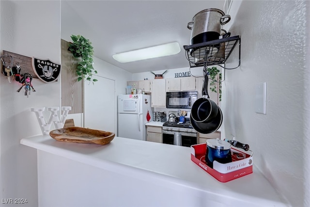 kitchen featuring white refrigerator, white cabinetry, and stainless steel gas stove