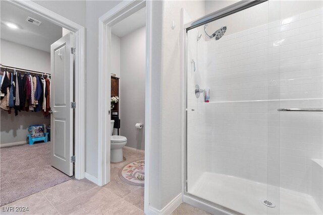 bathroom with toilet, a shower with shower door, and tile patterned flooring