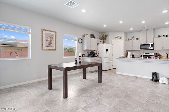 kitchen with light tile patterned floors, white refrigerator with ice dispenser, white cabinets, and stove