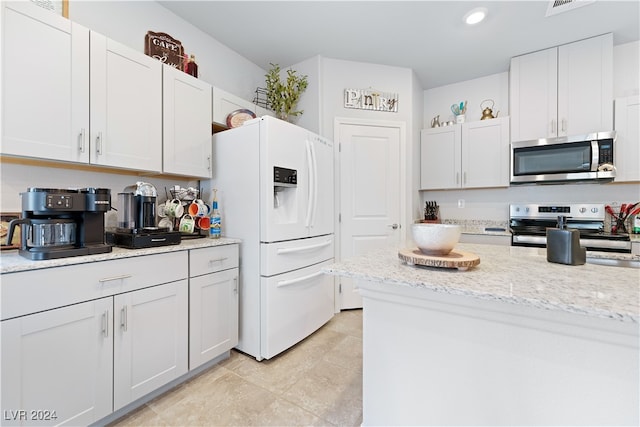 kitchen with appliances with stainless steel finishes, white cabinetry, light tile patterned floors, and light stone counters