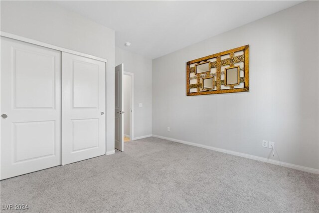 unfurnished bedroom with light carpet and a closet