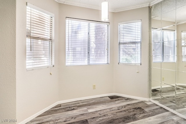 empty room with hardwood / wood-style flooring, a textured ceiling, and ornamental molding