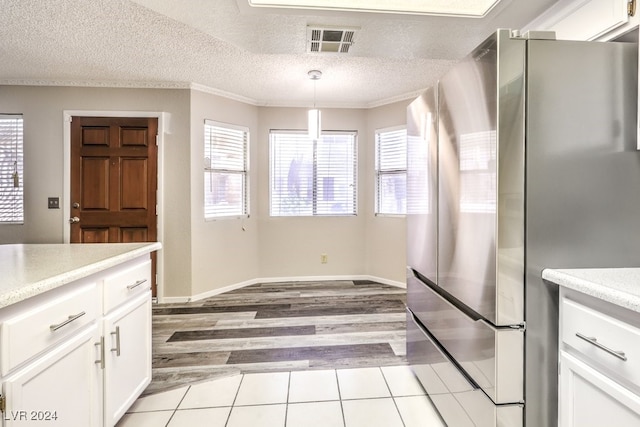 kitchen with white cabinetry, stainless steel refrigerator, a textured ceiling, light hardwood / wood-style floors, and pendant lighting