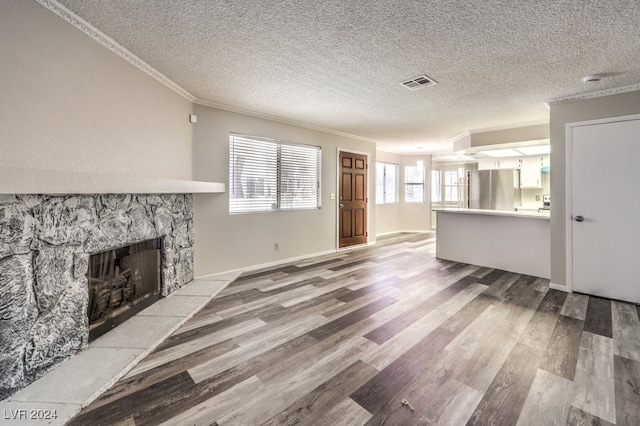 unfurnished living room with a textured ceiling, a fireplace, hardwood / wood-style flooring, and crown molding