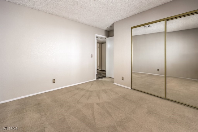 unfurnished bedroom with light carpet, a closet, and a textured ceiling