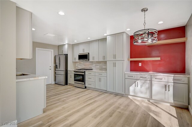 kitchen featuring decorative backsplash, light wood-type flooring, stainless steel appliances, and gray cabinets