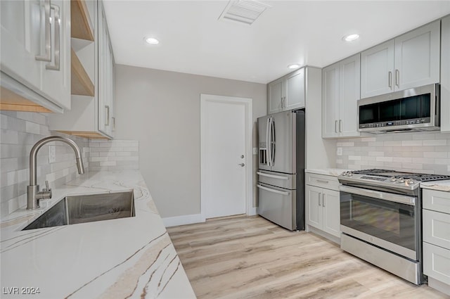 kitchen featuring visible vents, light stone counters, stainless steel appliances, and a sink