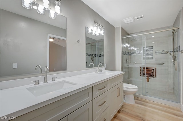 bathroom featuring wood finished floors, a sink, toilet, and a shower stall