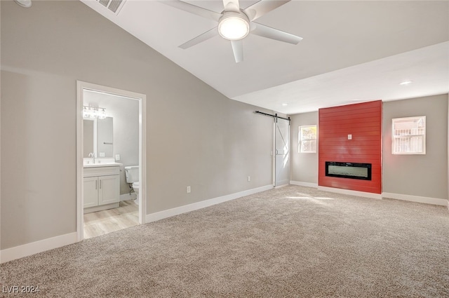 unfurnished living room featuring light carpet, vaulted ceiling, visible vents, and a barn door