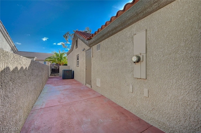 view of side of property with stucco siding, central AC unit, a gate, a patio area, and fence