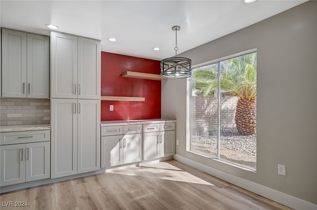 kitchen with pendant lighting, light wood finished floors, open shelves, gray cabinets, and baseboards