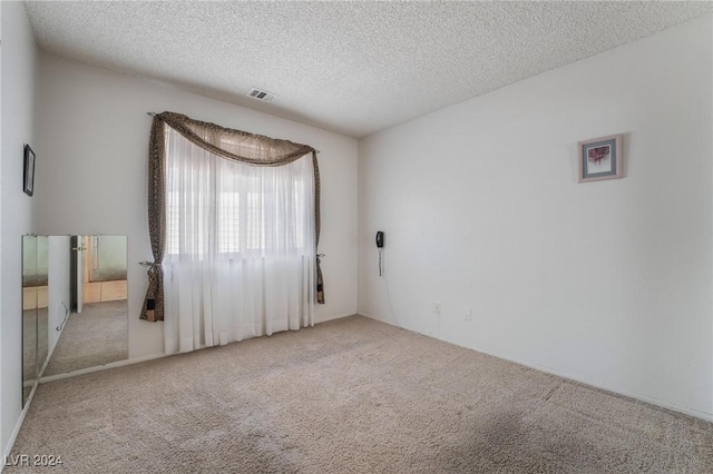 unfurnished room featuring carpet, visible vents, and a textured ceiling