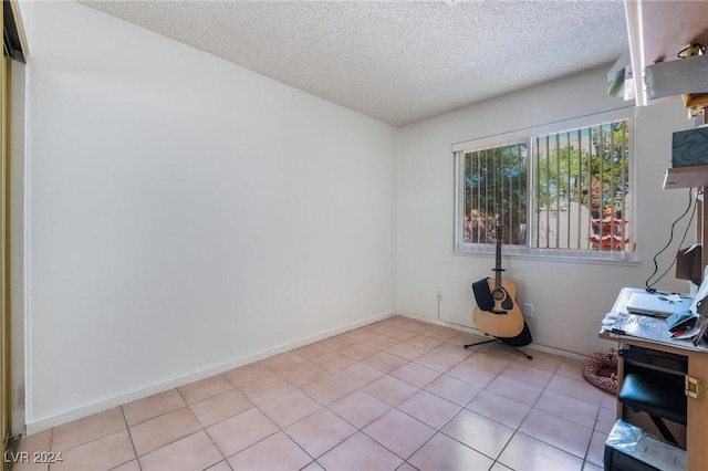 unfurnished office featuring a textured ceiling, light tile patterned floors, and baseboards