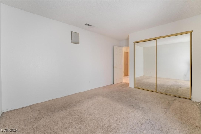 unfurnished bedroom with carpet floors, a textured ceiling, visible vents, and a closet