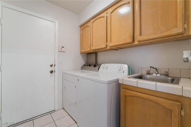 clothes washing area featuring cabinet space, light tile patterned floors, a sink, and washing machine and clothes dryer