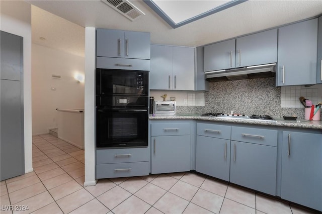 kitchen featuring light tile patterned floors, under cabinet range hood, visible vents, backsplash, and stainless steel gas stovetop