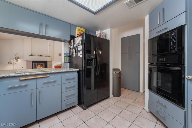 kitchen featuring black appliances, light tile patterned flooring, visible vents, and blue cabinets