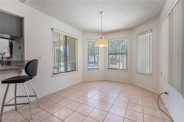 dining area with light tile patterned floors, a textured ceiling, and baseboards