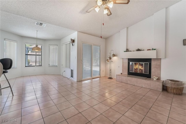 unfurnished living room featuring light tile patterned floors, visible vents, ceiling fan, a textured ceiling, and a fireplace