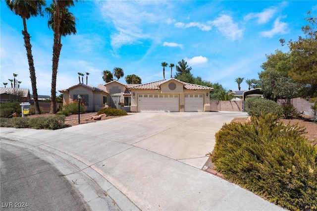 mediterranean / spanish-style house featuring a tile roof, stucco siding, concrete driveway, an attached garage, and fence