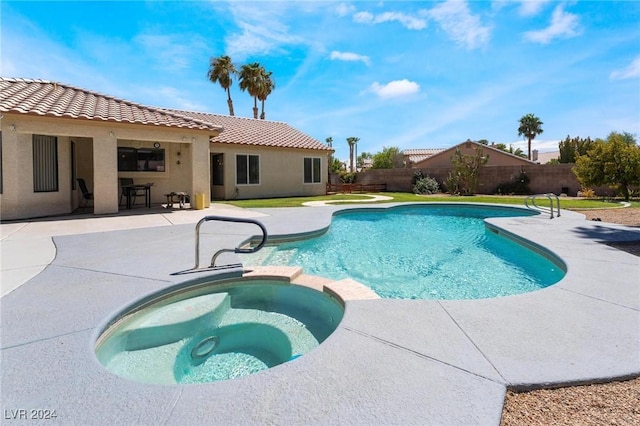 view of pool with a pool with connected hot tub, fence, and a patio