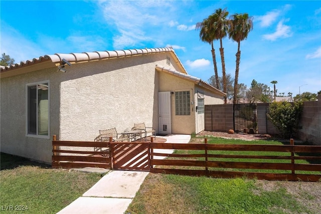 view of side of property with a tile roof, fence private yard, and stucco siding