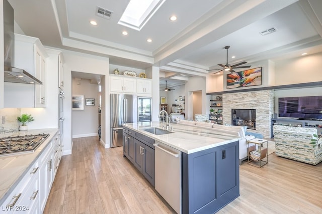 kitchen with visible vents, white cabinetry, open floor plan, appliances with stainless steel finishes, and wall chimney exhaust hood