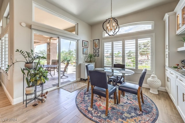 dining space with baseboards, light wood-type flooring, and an inviting chandelier