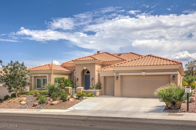 mediterranean / spanish-style house featuring a garage, concrete driveway, a tile roof, and stucco siding