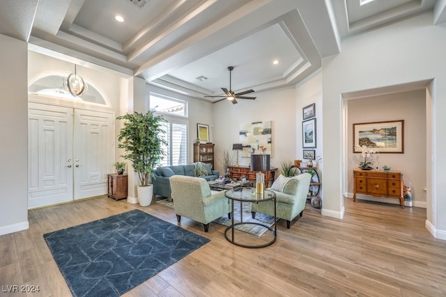 living room with a raised ceiling, wood-type flooring, a towering ceiling, and ceiling fan